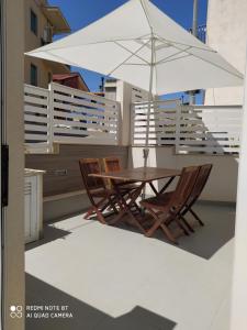 a table and two chairs and an umbrella on a balcony at Iris in Marina di Ragusa