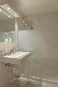 a white bathroom with a sink and a shower at Hotel dala in Leukerbad