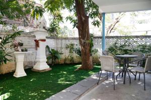 a garden with a table and chairs and a tree at Rubin Home in Bangkok