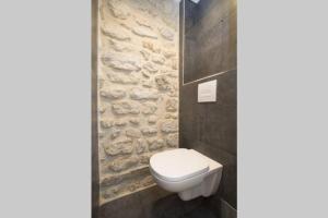 巴黎的住宿－The Designer Apartment，浴室配有白色卫生间和石墙。
