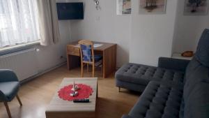 ein Wohnzimmer mit einem Sofa, einem Tisch und einem Schreibtisch in der Unterkunft Apartment Zur Kogge in Wilhelmshaven