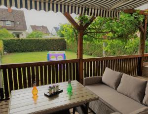 un patio con una mesa y un sofá en una terraza en Familienfreundliches Ferienhaus AMARA mit Garten und Terrasse - Friedrichshafen am Bodensee, en Friedrichshafen