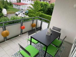 a balcony with a black table and green chairs at Anytime - Ferienwohnung Rita in Friedrichshafen in Friedrichshafen