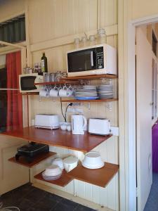 a kitchen with a shelf with microwaves and a microwave at Golden Mt Rest on James in Mount Morgan