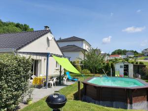 une cour avec une piscine entourée d'un parasol vert dans l'établissement Villa du pic vert 105m2 , 4 chambres de plain-pied avec piscine à Montfaucon, à Montfaucon