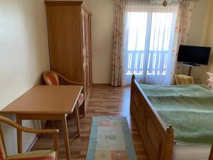 a bedroom with a bed and a table and a desk at Hotel Garni Haus am Wald in Reifnitz