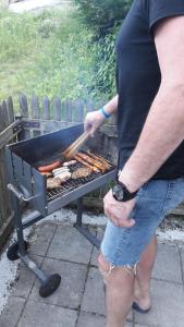a man is cooking sausages on a grill at Maridl`s Ferienhaus in Umhausen