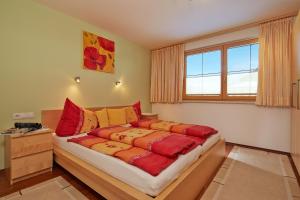 1 dormitorio con 1 cama con almohadas rojas y amarillas en Apart Sunshine, en Längenfeld