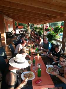 grupa ludzi siedzących przy długim stole jedzących jedzenie w obiekcie VILLA NIKOLINA w Medulinie