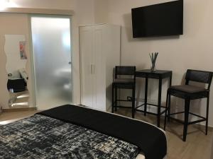 een slaapkamer met een bed, 2 krukken en een televisie bij La casetta di viale Paradiso in Pachino