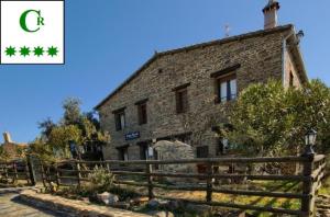 una vieja casa de piedra con una valla delante de ella en Casa Rural Al-Mofrag y Apartamentos El Mirador de Monfragüe, en Villarreal de San Carlos