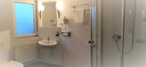 a white bathroom with a shower and a sink at Landhotel Schuff in Kindsbach