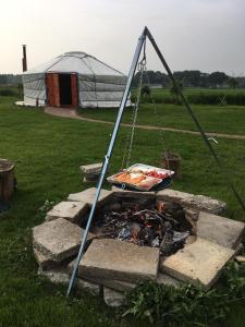 a grill over a fire with a tent in the background at Iloons yurt in Hollandscheveld