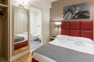 パレルモにあるBelmonte102 Esclusive Suitesの赤いヘッドボードと鏡付きのベッドルーム