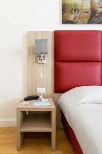 パレルモにあるBelmonte102 Esclusive Suitesのベッド1台(赤いヘッドボード付)、テーブル(電話付)