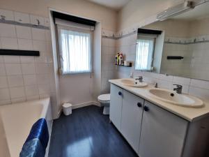 La salle de bains est pourvue de 2 lavabos, d'une baignoire et de toilettes. dans l'établissement Le Petit Michelet, à Granville