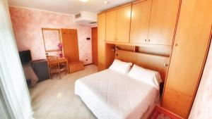 um pequeno quarto com uma cama branca e uma secretária em Hotel & Wellness Fra I Pini em Lignano Sabbiadoro