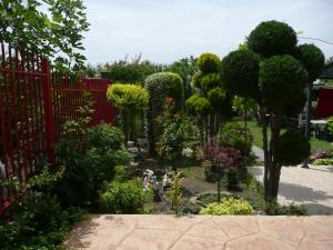 a garden with trees and bushes next to a red fence at Dimitrovi Guest House in Aheloy