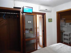 a bedroom with a tv on top of a glass door at Ex Pousada Vale do Bosque - Aluguel por temporada in Gramado