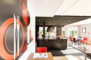 a dining room with red chairs and a restaurant at KYRIAD Issoudun in Issoudun