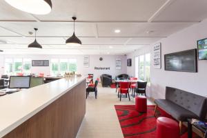 a waiting room with red chairs and a long counter at KYRIAD Issoudun in Issoudun