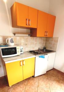 una pequeña cocina con armarios naranjas y microondas en CECILLIA Mare Apartments, en Rovinj