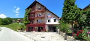 a red and white building on the side of a road at Prenociste DUGA in Užice