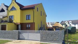 a yellow house with a fence in front of it at TOBI-pokoje gościnne in Łeba