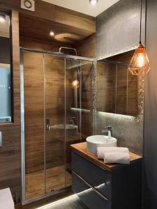 a bathroom with a glass shower and a sink at Apartamenty Silence Baltic Indygo in Pobierowo