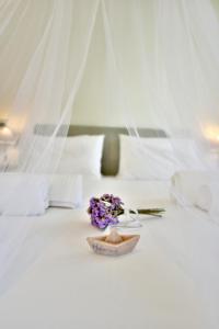 a bouquet of purple flowers on a bed at Onar Hydra in Hydra