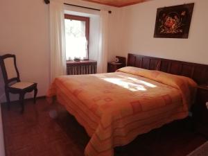 une chambre avec un lit, une chaise et une fenêtre dans l'établissement Appartamenti nonna Carmen, à Sappada