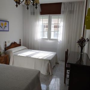 een slaapkamer met 2 bedden en een raam bij Acogedor apartamento céntrico in O Grove