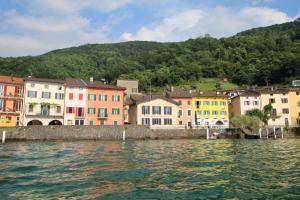 a group of colorful houses next to a body of water at Dolceresio Lugano Lake B&B in Brusino Arsizio