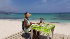 a woman sitting at a table on the beach at Villa Rosa in Punta Rucia