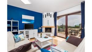 Holiday Home Bellavista في تار: غرفة معيشة بجدران زرقاء وأريكة بيضاء