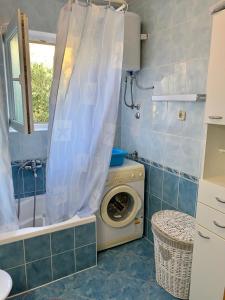 a bathroom with a washing machine and a shower curtain at Apartments Marina in Rab