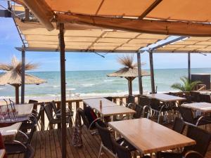 ein Restaurant im Freien mit Tischen, Stühlen und Meerblick in der Unterkunft Beach, Wine, Dining, Sports, Summer, Winter in Sérignan