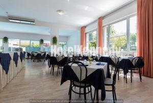 un salón de banquetes con mesas, sillas y ventanas en Hotel Kennedy, en Lido di Savio