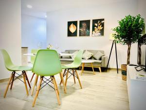 a dining room with green chairs and a table at Apartamentos Villas Romanas in Mérida