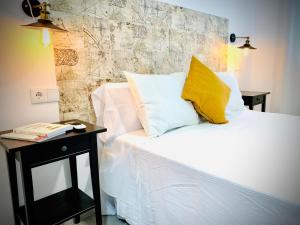 a bed with white sheets and yellow pillows next to a table at Apartamentos Villas Romanas in Merida