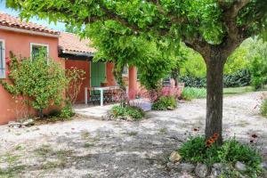 a house with a table and a tree in the yard at Villa piscine face au grand luberon Cereste in Céreste