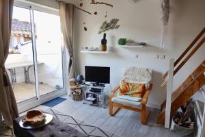 ein Wohnzimmer mit einem Stuhl und einem TV in der Unterkunft Beach, Wine, Dining, Sports, Summer, Winter in Sérignan