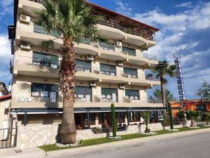 a tall building with a palm tree in front of it at Tropicana in Paralia Katerinis