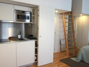 cocina con armarios blancos, microondas y escalera en Vila Baixa - alojamento local, en Guimarães