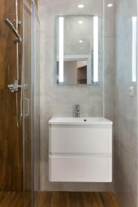 ein Badezimmer mit einem weißen Waschbecken und einem Spiegel in der Unterkunft Apartments on Kulisha str in Lwiw
