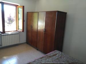 ein Schlafzimmer mit einem Holzschrank und einem Fenster in der Unterkunft Casetta indipendente al lago di Bolsena in Valentano