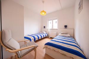 een kamer met twee bedden en een stoel erin bij Apartments Leonarda in Murter