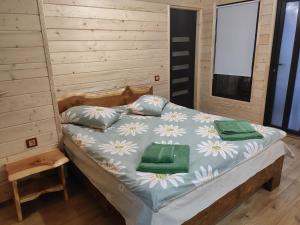 a bed in a wooden room with two green towels on it at Нота Карпат in Skole