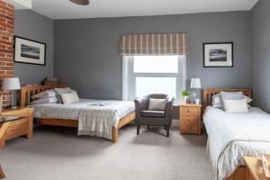 a bedroom with two beds and a chair and a window at The Caledon Guest House in Cowes