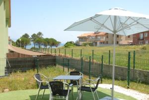a table and chairs with an umbrella and a playground at Apartamentos Loncho Finisterre in Fisterra